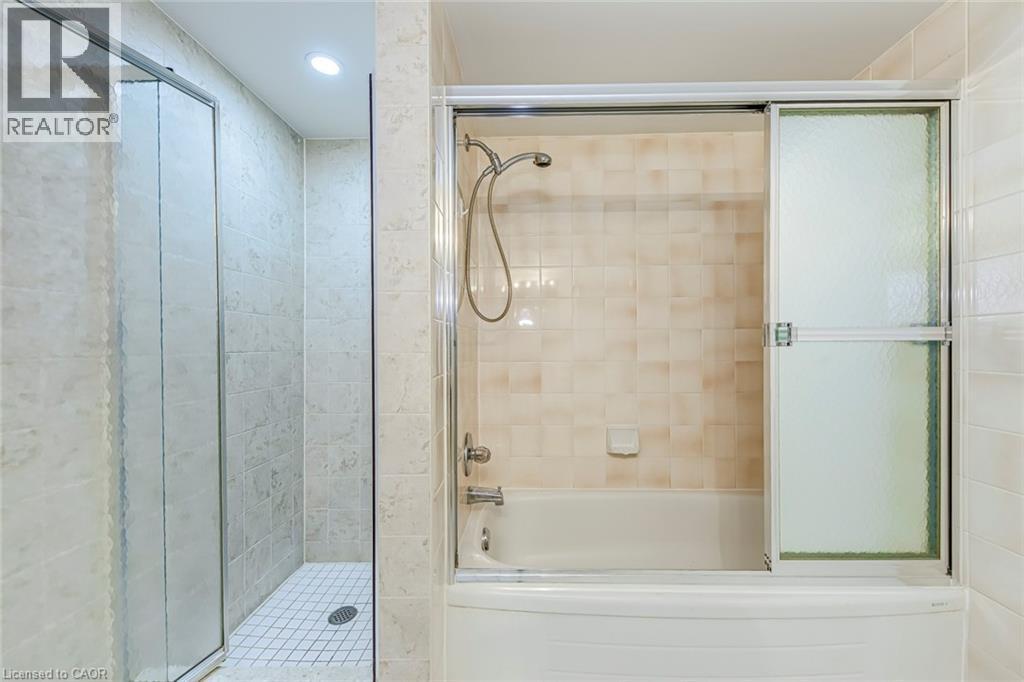 Bathroom featuring a tiled walk-in shower with a glass enclosure and an additional bathtub with a sliding frosted glass door - 1270 Maple Crossing Boulevard Unit# 1705, Burlington, ON - Indoor Photo Showing Bathroom