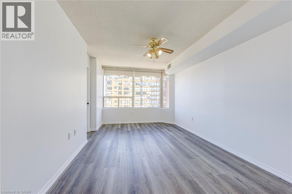 Spacious room with wood-finish flooring, white walls, and a large window with white blinds - 1270 Maple Crossing Boulevard Unit# 1705, Burlington, ON - Indoor Photo Showing Other Room
