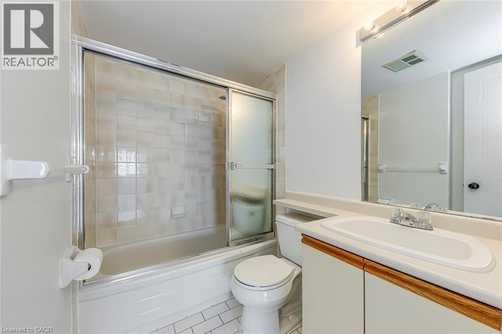 Bathroom featuring a built-in vanity with laminate countertop, integrated sink, and wood-finish cabinet doors - 1270 Maple Crossing Boulevard Unit# 1705, Burlington, ON - Indoor Photo Showing Bathroom