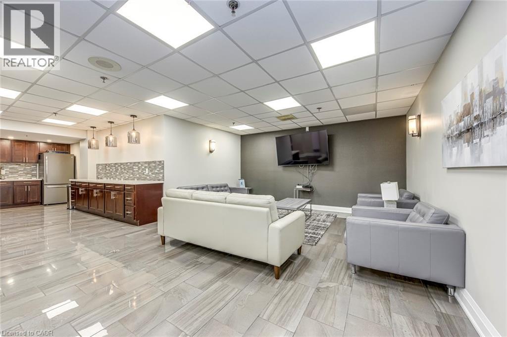 Spacious common area featuring wood-finish flooring, a full kitchen with stainless steel appliances, and abundant recessed lighting - 1270 Maple Crossing Boulevard Unit# 1705, Burlington, ON - Indoor
