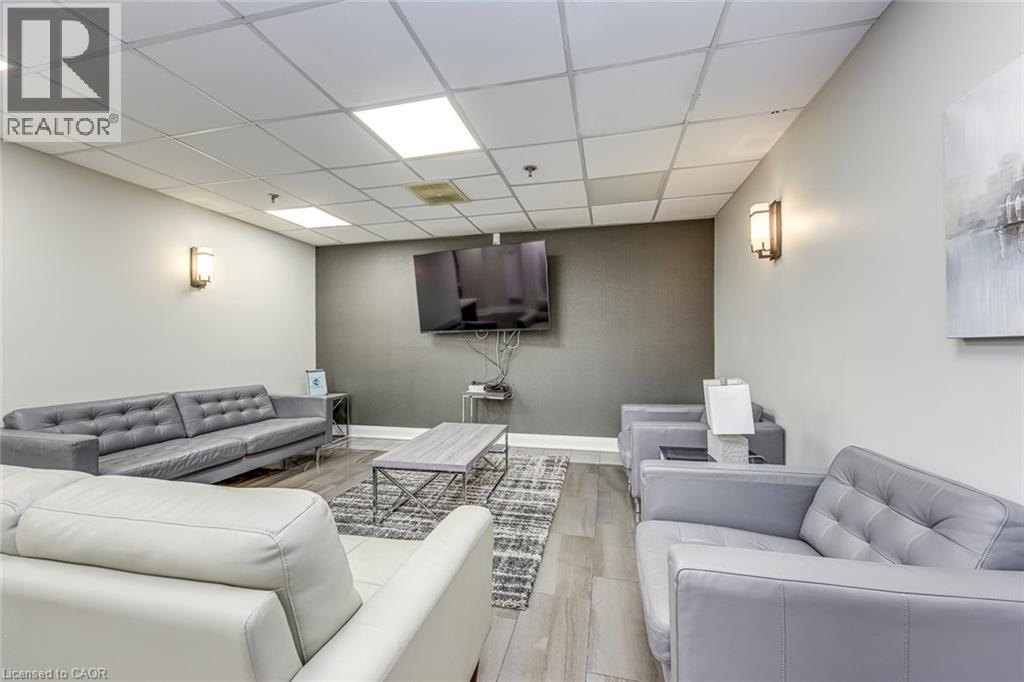 Spacious lounge area featuring neutral wall tones and a distinct accent wall - 1270 Maple Crossing Boulevard Unit# 1705, Burlington, ON - Indoor Photo Showing Other Room