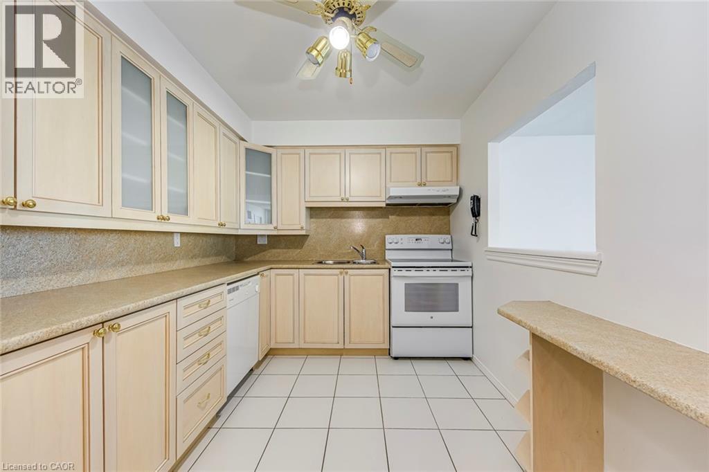 Kitchen featuring extensive light-toned cabinetry with gold-toned hardware, a stone-finish backsplash, and matching countertops - 1270 Maple Crossing Boulevard Unit# 1705, Burlington, ON - Indoor Photo Showing Kitchen