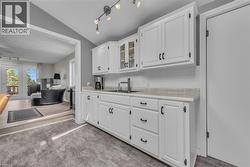 Kitchen featuring white cabinetry with black hardware, a subway tile backsplash, and light-toned countertops -