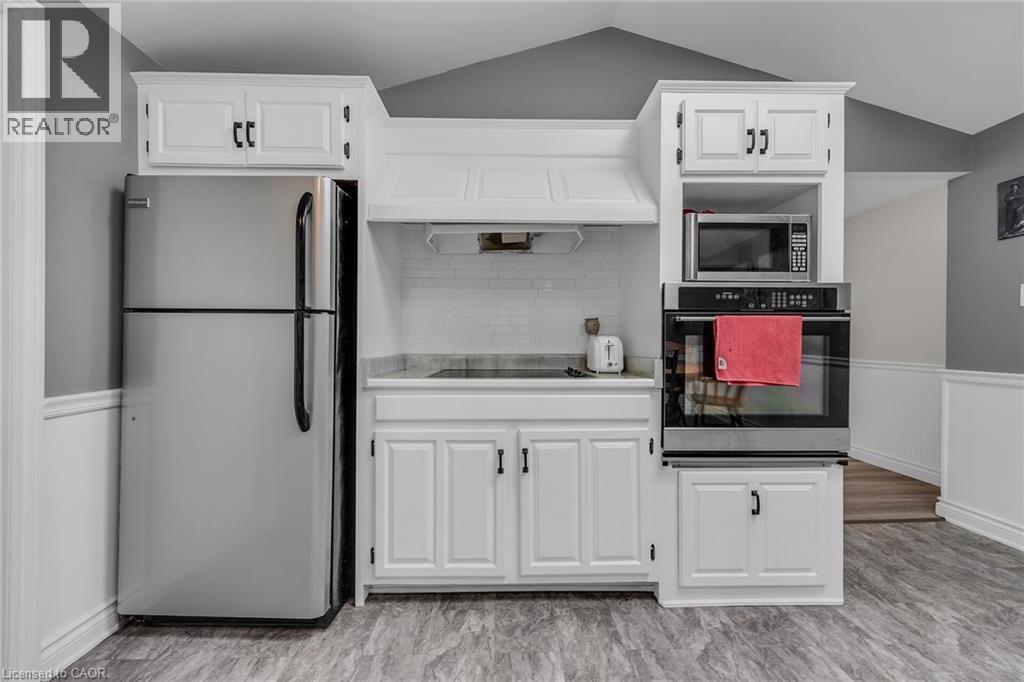 Kitchen featuring white cabinetry with dark hardware, stainless steel appliances, a built-in microwave, and an electric cooktop - 270 Erie Boulevard, Long Point, ON - Indoor Photo Showing Kitchen