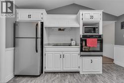 Kitchen featuring white cabinetry with dark hardware, stainless steel appliances, a built-in microwave, and an electric cooktop -