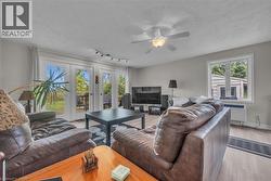 Living area with light wood-finish flooring, light gray wall paint, and a ceiling fan with integrated lighting -