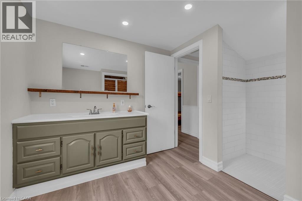 Bathroom featuring a vanity with a white countertop and sage green cabinetry, a recessed sink, and a wall-mounted mirror - 270 Erie Boulevard, Long Point, ON - Indoor
