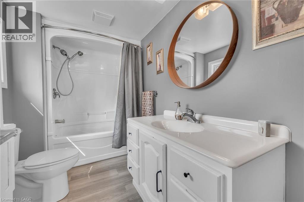 Bathroom featuring a white vanity with integrated sink, wood-finish flooring, and a white bathtub with shower combination - 270 Erie Boulevard, Long Point, ON - Indoor Photo Showing Bathroom