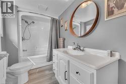 Bathroom featuring a white vanity with integrated sink, wood-finish flooring, and a white bathtub with shower combination -