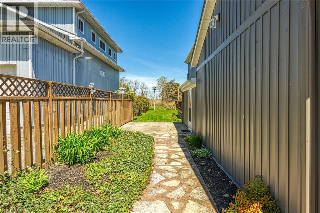 Stone-paver pathway bordered by established landscaping and a wooden privacy fence - 270 Erie Boulevard, Long Point, ON - Outdoor With Exterior