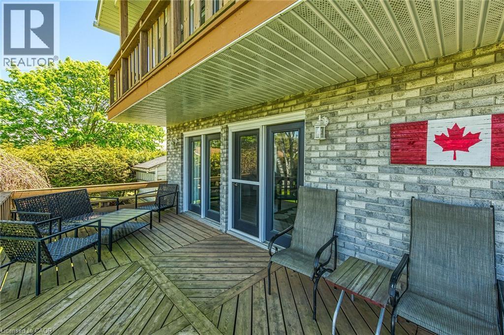 Spacious outdoor deck featuring wood flooring with a geometric pattern, direct access through two glass-paneled doors, and an overhead balcony - 270 Erie Boulevard, Long Point, ON - Outdoor With Deck Patio Veranda With Exterior