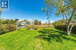 Expansive green lawn with mature trees and a tranquil pond feature -