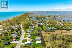 Aerial perspective showcasing a residential community situated between a large body of water and expansive wetlands -