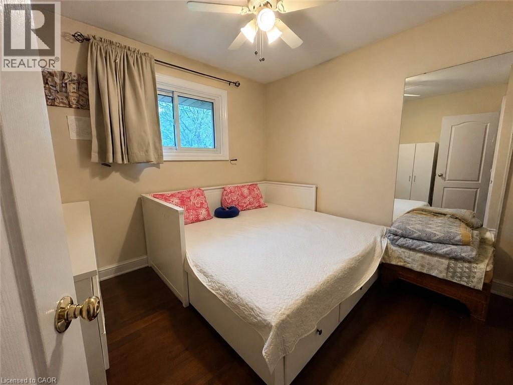 Bedroom featuring wood-finish flooring, a ceiling fan with light fixture, and a window with a curtain rod - 917 Orpha Street, Burlington, ON - Indoor Photo Showing Bedroom