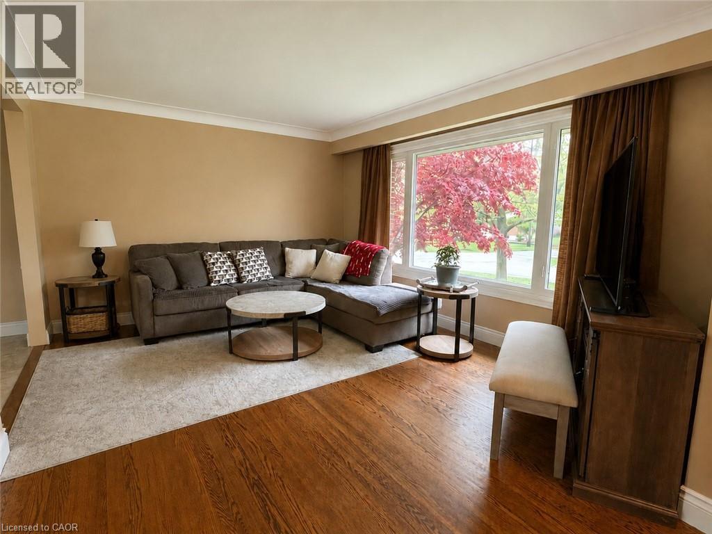 Spacious living area featuring rich wood-finish flooring, a large picture window, crown molding, and neutral wall tones - 917 Orpha Street, Burlington, ON - Indoor Photo Showing Living Room