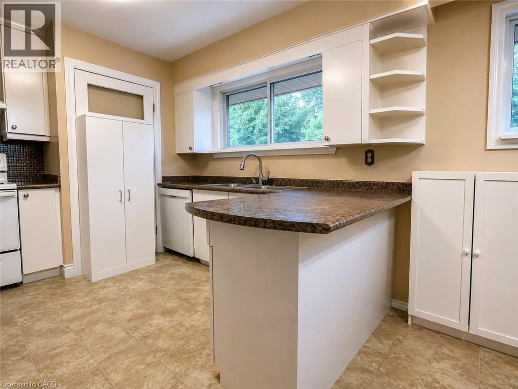 Kitchen featuring white cabinetry, a brown speckled countertop, and light-toned tile flooring - 917 Orpha Street, Burlington, ON - Indoor Photo Showing Kitchen With Double Sink