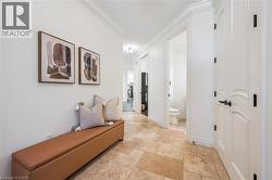 Hallway featuring natural stone tile flooring, white crown molding, and white paneled doors with dark hardware. -