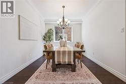 Dining area featuring dark wood-finish flooring, white baseboards, and crown molding. -