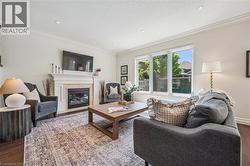 Living area featuring a gas fireplace with a stone surround, white mantel, and wood-finish flooring. -