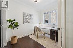 Bright office with dark wood-finish flooring, white walls, and a window with white trim. -