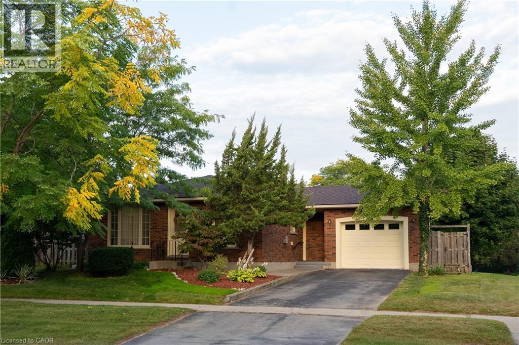 View of property hidden behind natural elements featuring brick siding, driveway, and an attached garage - 32 Donly Drive N, Simcoe, ON - Outdoor