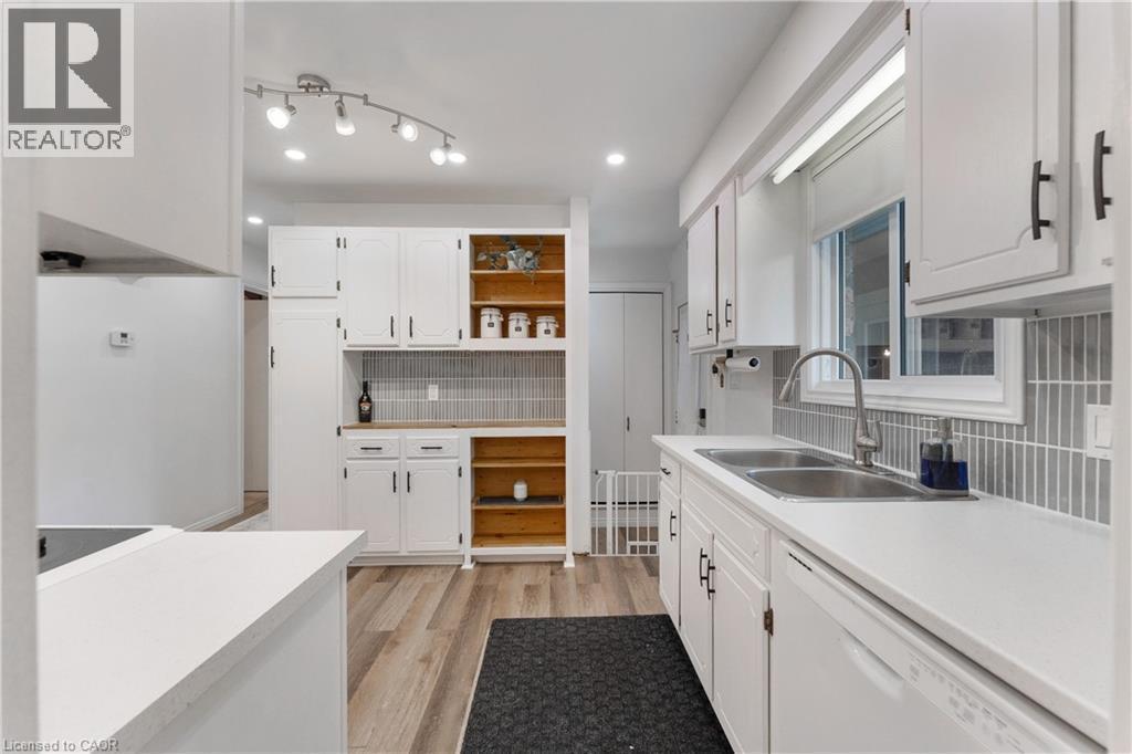 Bright kitchen with white cabinetry, wood-finish flooring, and a subway tile backsplash - 32 Donly Drive N, Simcoe, ON - Indoor Photo Showing Kitchen With Double Sink