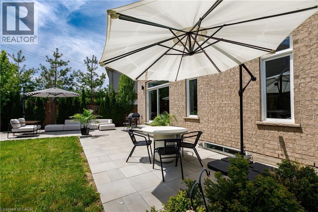Spacious patio area featuring light-toned paver stones, a substantial umbrella, and direct access to the interior via a glass sliding door - 916 Steepleridge Court, Kitchener, ON - Outdoor