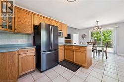 Kitchen featuring light wood cabinetry, light-toned tiled flooring, and a contemporary pendant light fixture -