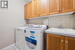 Laundry area featuring wood cabinetry, a utility sink with laminate countertop, and square tile backsplash -