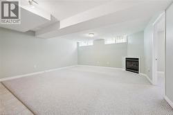 Spacious carpeted room featuring a built-in fireplace, light-colored walls, white trim, and a doorway -