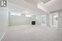 Spacious room featuring light-colored carpeting, a built-in electric fireplace, and recessed lighting -