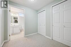 Carpeted room featuring light green walls, white trim, and two paneled bi-fold closet doors -