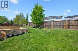 Expansive backyard featuring a large wood deck with lattice skirting, a substantial lawn area, mature trees, and privacy fencing -