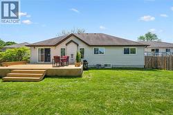Expansive backyard featuring a large wooden deck with steps, direct access via sliding glass doors, and a manicured lawn -