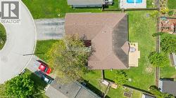 Aerial perspective showcasing the property with a brown shingle roof, a generously sized backyard, and a wooden deck -