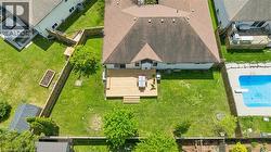 Expansive backyard featuring a wood deck with stairs, a manicured lawn, perimeter fencing, and mature trees -