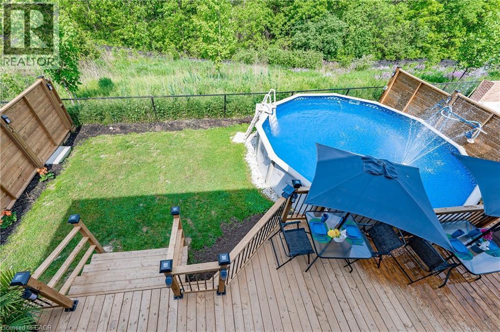 Elevated wood deck with black metal balusters and post cap lighting - 9 Fleming Crescent, Caledonia, ON - Outdoor With Above Ground Pool