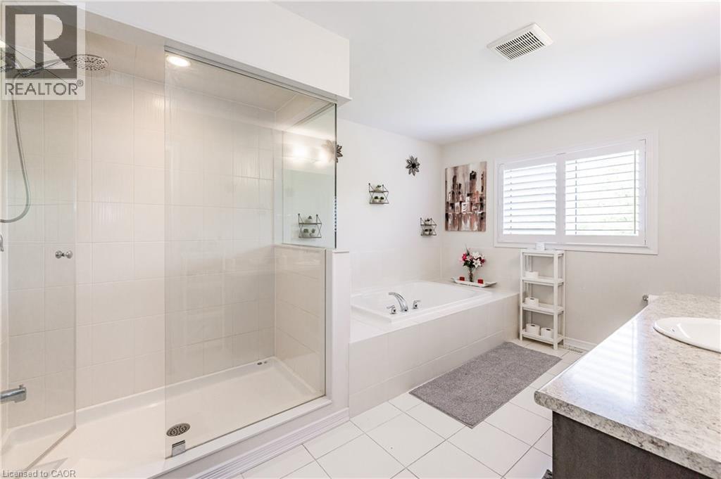Bathroom featuring a glass-enclosed shower, a built-in tub with deck-mounted fixtures, and a vanity with a light-toned countertop - 9 Fleming Crescent, Caledonia, ON - Indoor Photo Showing Bathroom