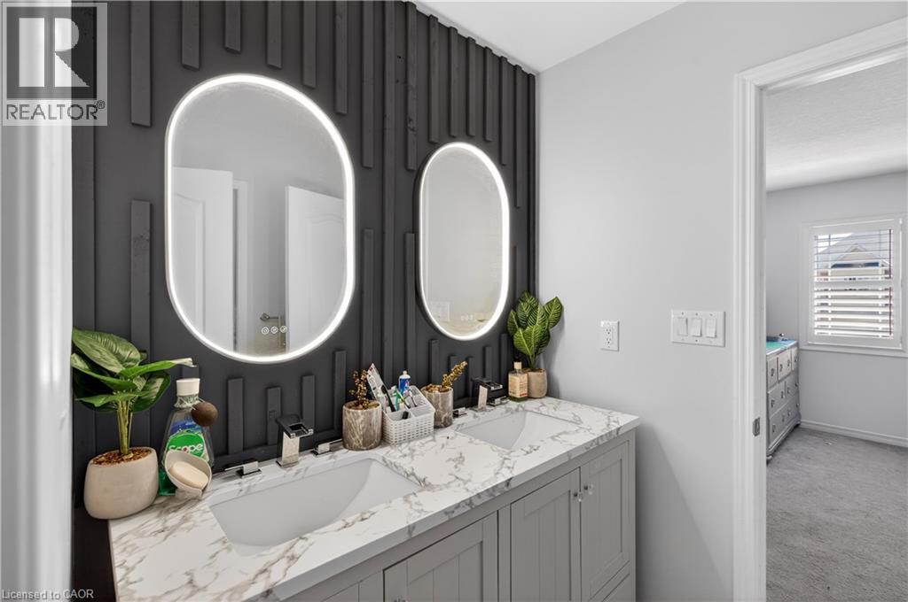 Dual oval LED-backlit mirrors accent a textured dark feature wall above a double vanity with a marble-finish countertop - 9 Fleming Crescent, Caledonia, ON - Indoor Photo Showing Bathroom