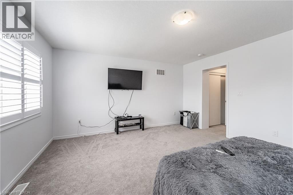 Carpeted room featuring white walls, window with white plantation shutters, and a ceiling-mounted light fixture - 9 Fleming Crescent, Caledonia, ON - Indoor Photo Showing Bedroom