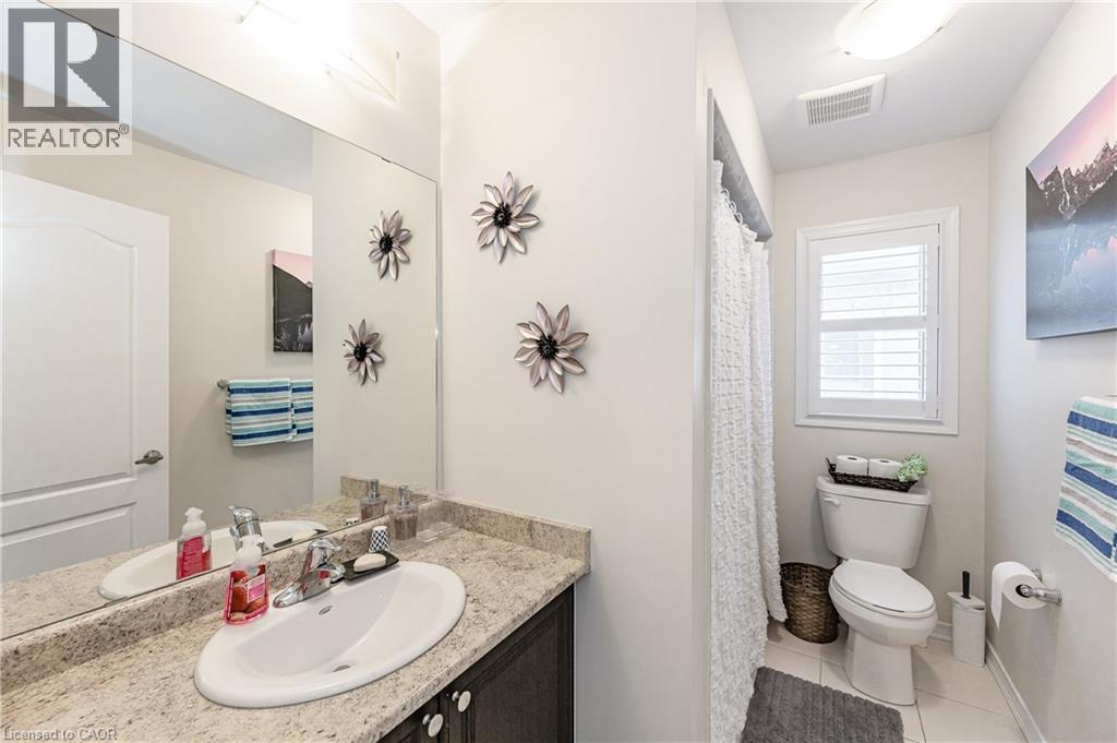 Bathroom featuring a dark wood-finish vanity with a light-colored countertop, an undermount sink, and a large wall-mounted mirror - 9 Fleming Crescent, Caledonia, ON - Indoor Photo Showing Bathroom