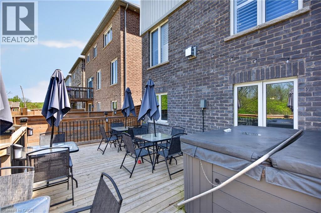 Expansive wood deck with a built-in hot tub, dark brick exterior, and multiple windows - 9 Fleming Crescent, Caledonia, ON - Outdoor With Deck Patio Veranda With Exterior