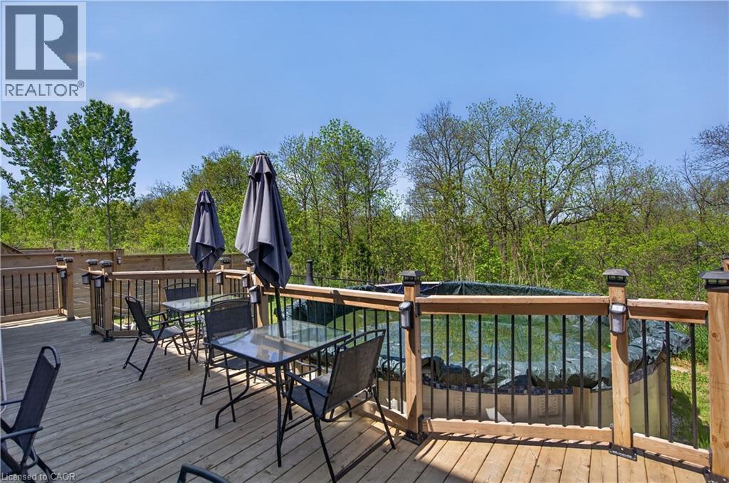 Expansive wooden deck with a built-in above-ground pool, surrounded by a wooden privacy fence and mature trees - 9 Fleming Crescent, Caledonia, ON - Outdoor With Deck Patio Veranda