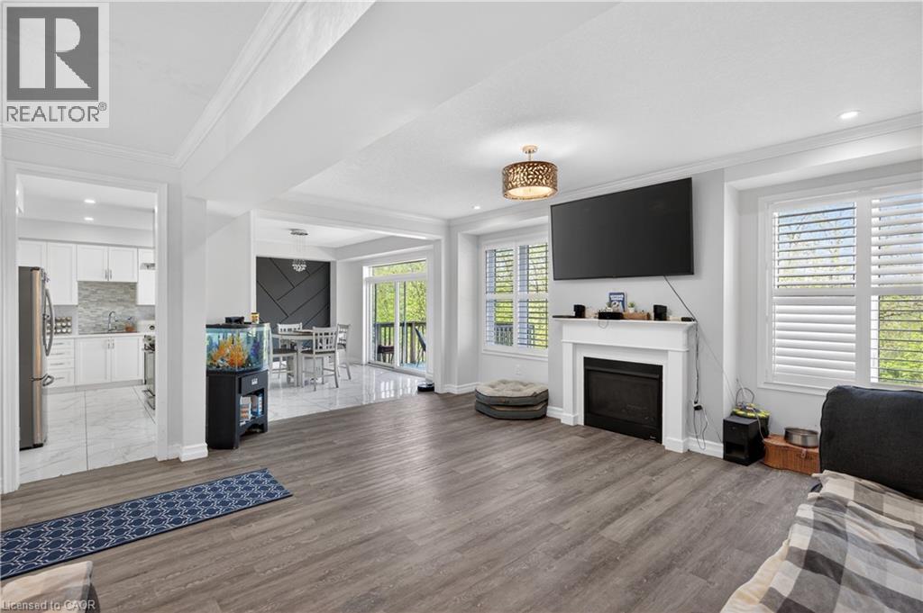 Spacious living area featuring wood-finish flooring, a white mantel fireplace, and multiple windows with plantation shutters - 9 Fleming Crescent, Caledonia, ON - Indoor With Fireplace