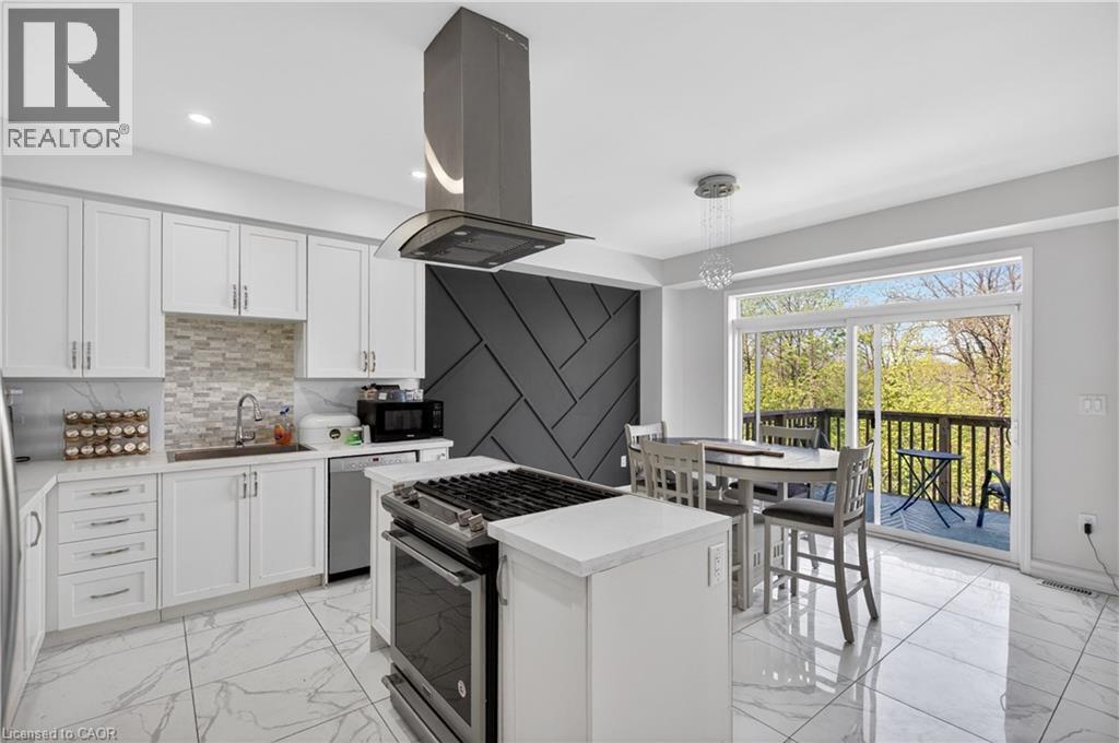 Contemporary kitchen featuring white cabinetry, a stone-finish backsplash, and a central island with a gas range - 9 Fleming Crescent, Caledonia, ON - Indoor Photo Showing Kitchen