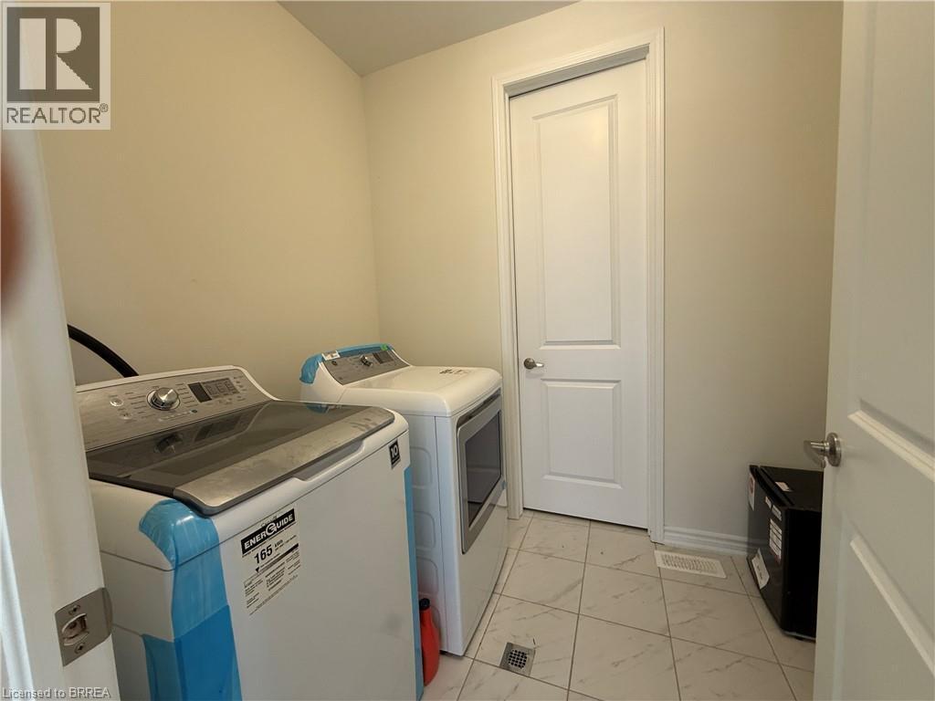 Laundry area featuring light-toned walls, a white paneled door with a silver knob, and light-toned square floor tiles - 18 Dolucci Crescent, Brampton, ON - Indoor Photo Showing Laundry Room