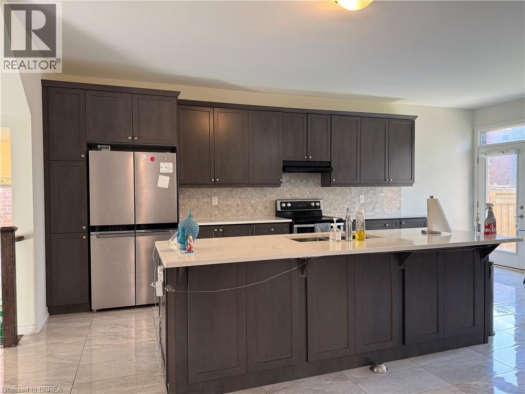 Modern kitchen featuring dark wood-finish cabinetry, stainless steel appliances, a center island with a light-toned countertop, a tile backsplash, and light-toned floor tiling - 18 Dolucci Crescent, Brampton, ON - Indoor Photo Showing Kitchen