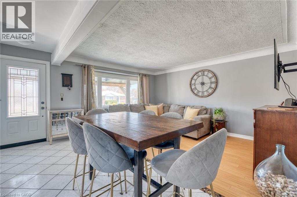 Open-concept living area featuring a prominent wood-finish counter-height table, light gray wall paint, and white trim - 151 Winchester Boulevard, Hamilton, ON - Indoor Photo Showing Dining Room