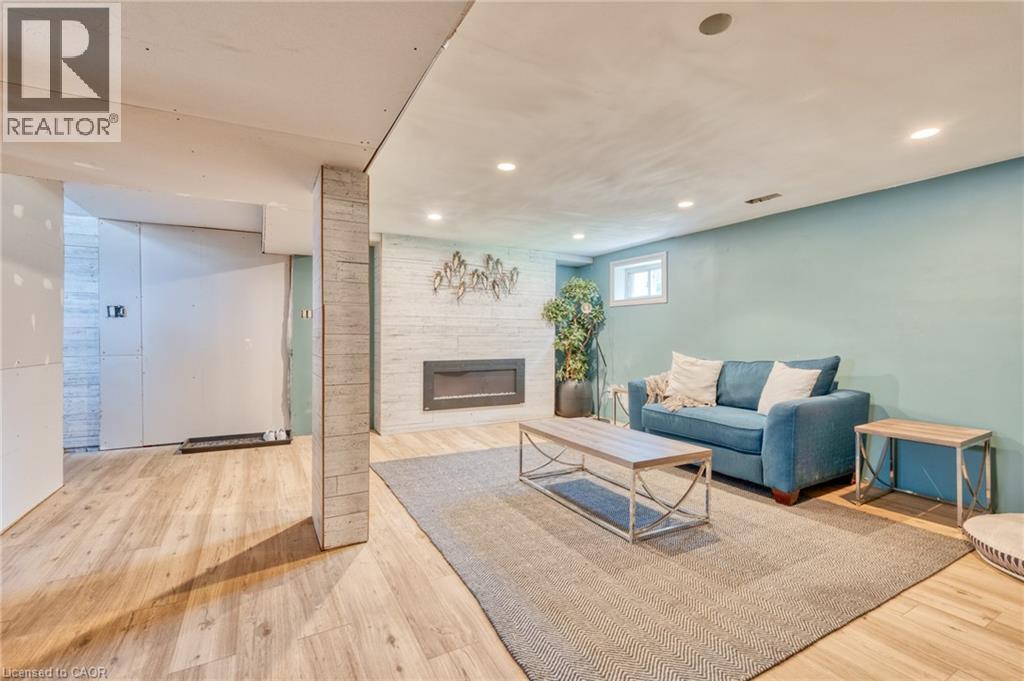 Spacious living area featuring wood-finish flooring, a contemporary fireplace with a stone-look surround, recessed lighting, and a window providing natural illumination - 151 Winchester Boulevard, Hamilton, ON - Indoor With Fireplace