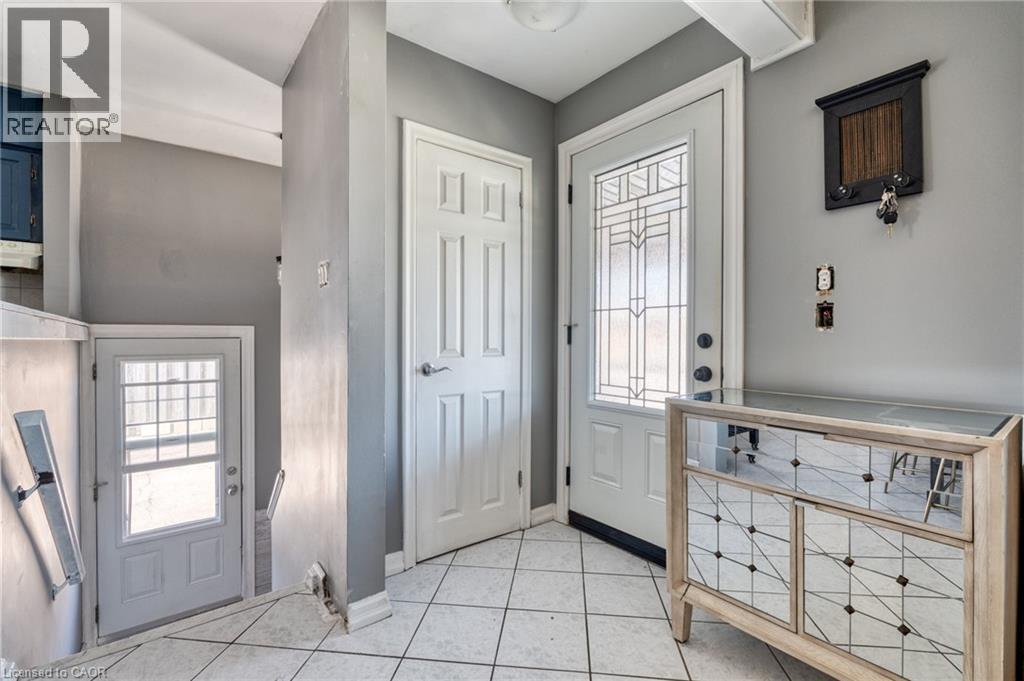 Entryway featuring white square floor tiles, a decorative front door with leaded glass, and an additional white paneled interior door - 151 Winchester Boulevard, Hamilton, ON - Indoor Photo Showing Other Room